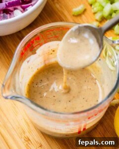 Whisking the creamy lemon-tahini dressing in a small bowl.