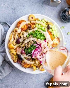 Adding dressing and fresh herbs to the bowl of roasted potatoes.