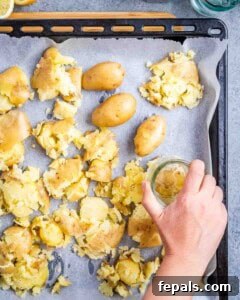 Smashing boiled potatoes on a baking sheet with a glass.