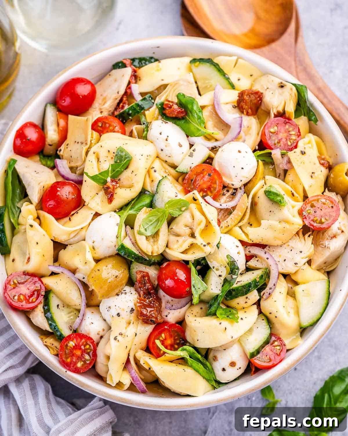 Zesty Italian Tortellini Toss 2 A large glass bowl filled with colorful tortellini pasta salad, featuring cherry tomatoes, mozzarella, and herbs.