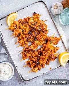 Yogurt marinated chicken on a sheet pan with lemon wedges.