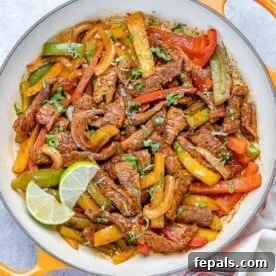 15-Minute Beef Dinners for Busy Weeknights 13 top view of steak fajitas in an orange skillet with lime wedges