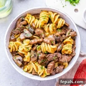 15-Minute Beef Dinners for Busy Weeknights 17 Freshly cooked stroganoff in a white bowl with rotini pasta, beef, and mushrooms mixed together.