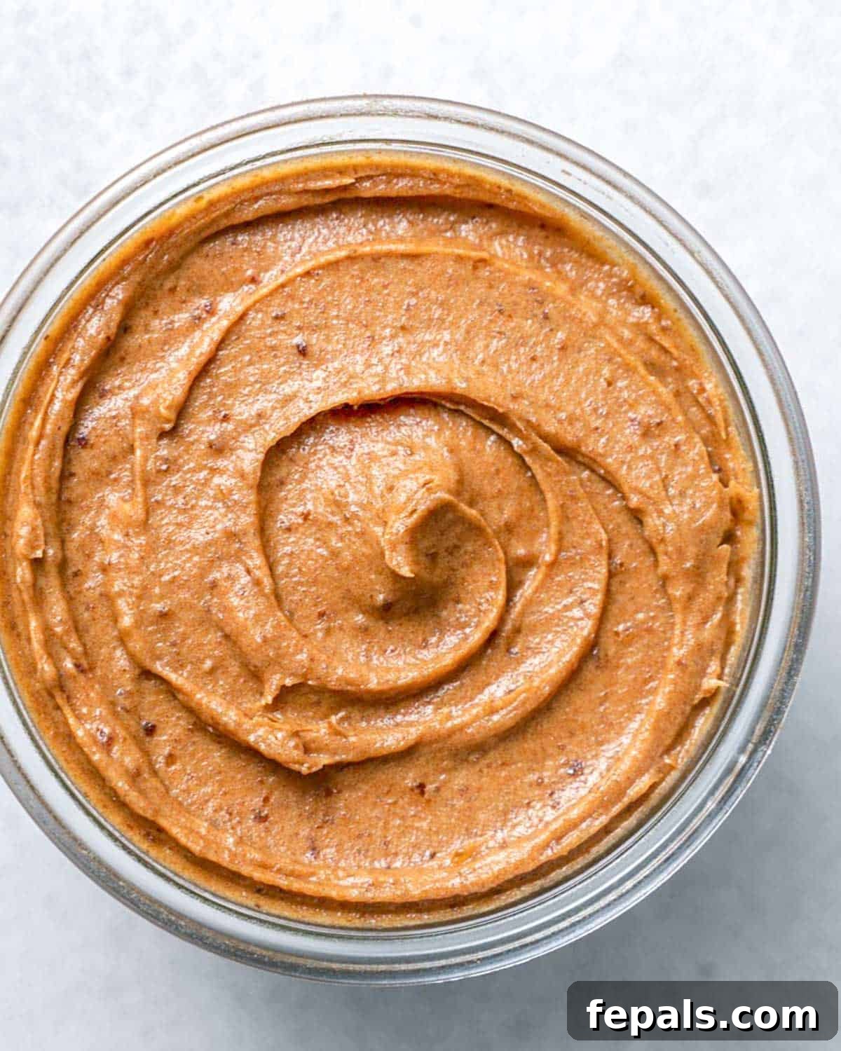 A glass jar filled with rich, brown homemade date paste, ready to be used as a natural sweetener.