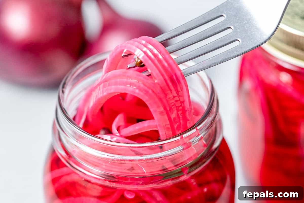 Quick Pickled Red Onions You’ll Prefer Over Store-Bought 8 fork grabbing pickled red onions in a jar.