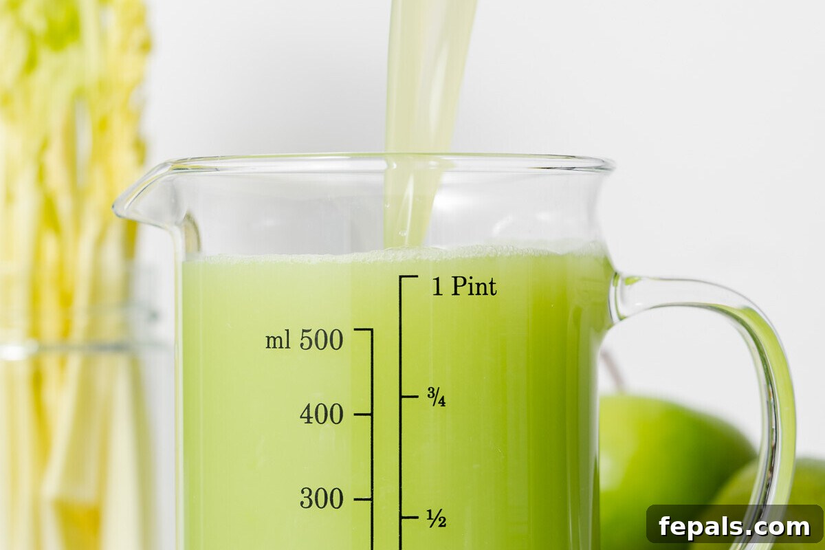 Straining celery juice from a blender into a glass jar using a fine-mesh sieve.