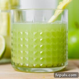 A close-up of a glass of celery juice, showing its vibrant green color.