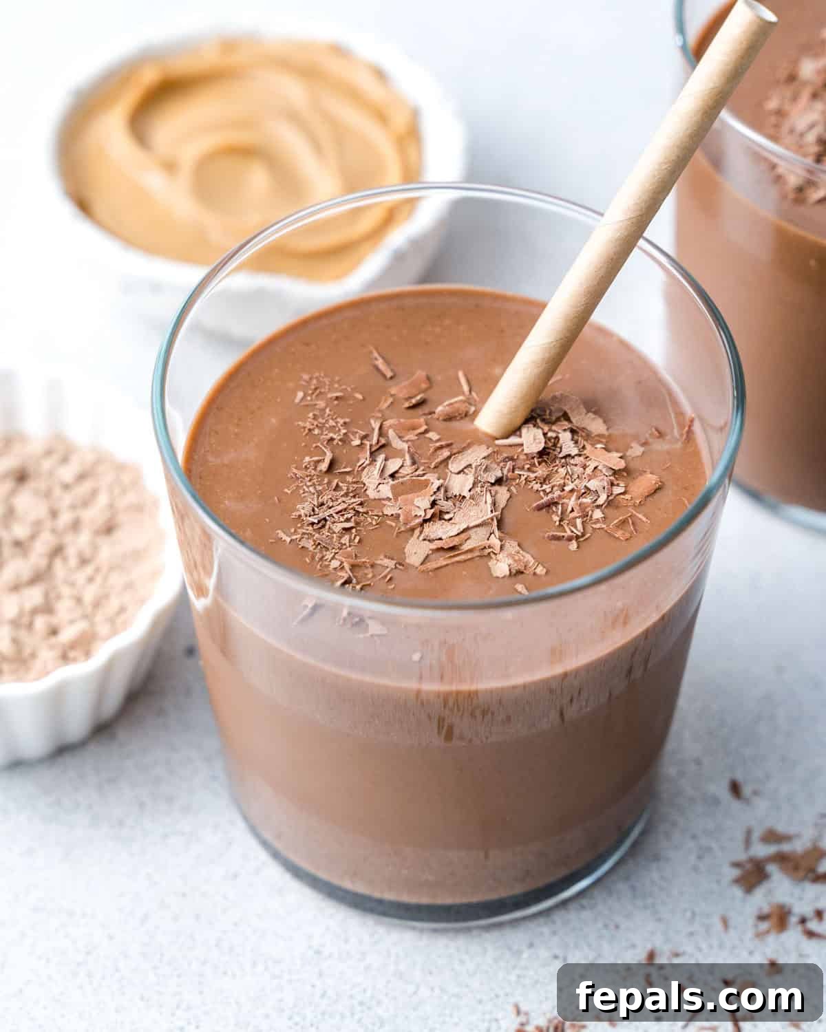 a cup butter chocolate protein shake  topped with chocolate shavings..