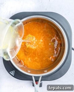 adding broth to the sauce in the pan.