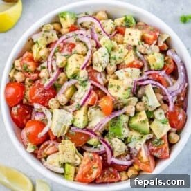 tomato chickpea onion and artichoke salad in white bowl