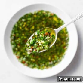 spoonful of chimichurri over a bowl of sauce