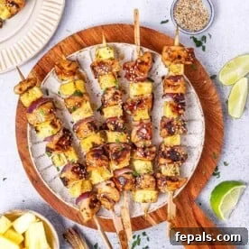 5 grilled chicken skewers on a white round plate.