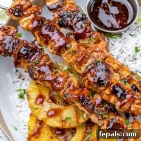 One stack of 3 chicken skewers on a plate of rice.