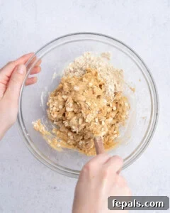 No-Bake Peanut Butter Oat Cups Recipe 11 hand mixing the peanut butter oat base in a bowl.