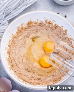 Soft Chewy Chocolate Chip Cookie Bars Recipe 11 two eggs added over whipped sugar and butter in a bowl.