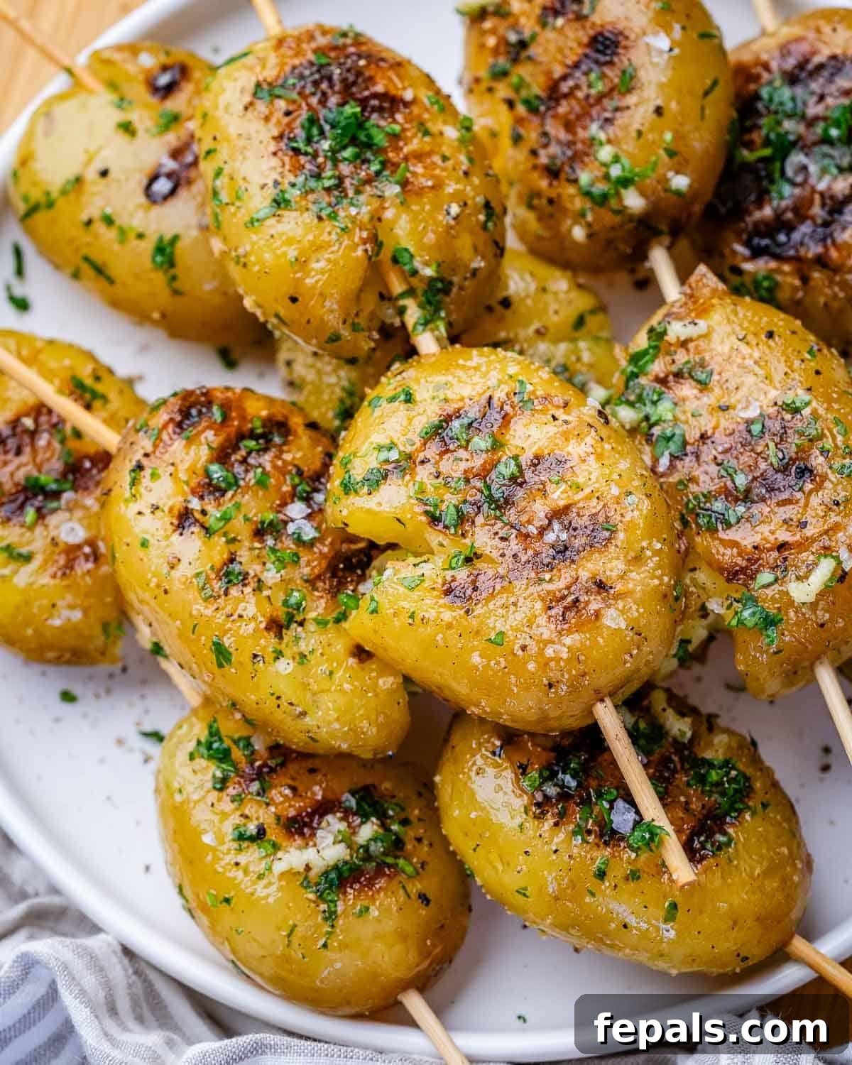 Grilled baby potatoes on skewers on a round white plate