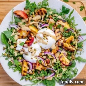 a plate with arugula salad topped with burrata and grilled peach.
