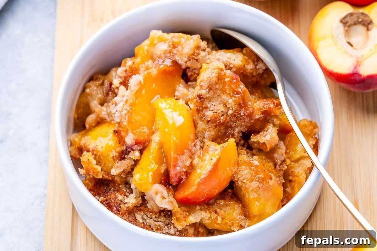 Fresh Peach Dump Cake Recipe with Ripe Peaches 6 peach dump cake in a round white bowl with a spoon in it.