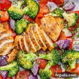 25 Chicken Meal Prep Recipes for Quick, Flavorful Weeknight Meals 14 top view sliced chicken breast on a sheet pan with roasted broccoli onions and red peppers