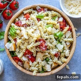 25 Chicken Meal Prep Recipes for Quick, Flavorful Weeknight Meals 18 chicken pasta salad in a round brown bowl with lettuce, pasta, chicken, and tomatoes.