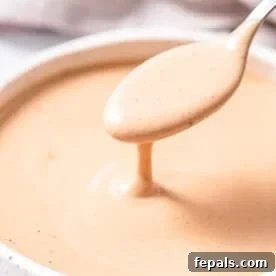 Homemade Copycat Raising Cane’s Sauce Recipe That Nails the Taste 7 a round bowl with copycat canes sauce with spoonful of sauce over bowl.