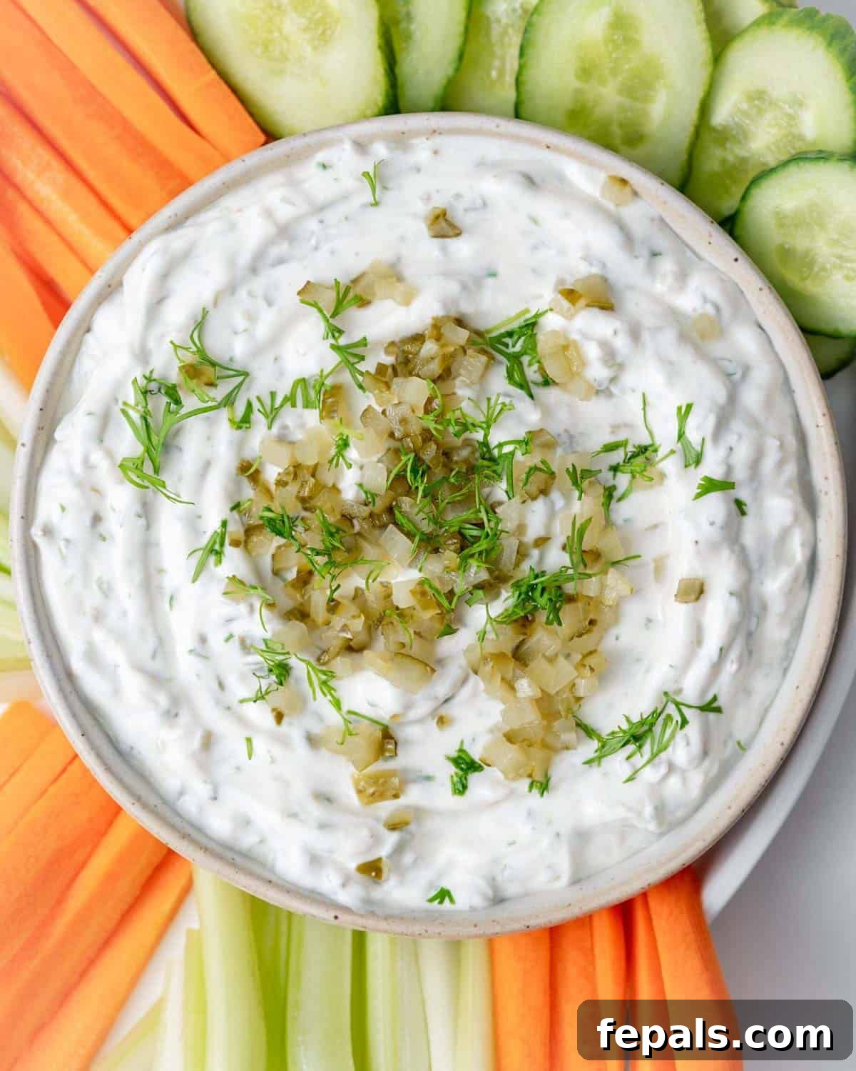 a bowl with dill pickle dip surrounded by sliced veggies.