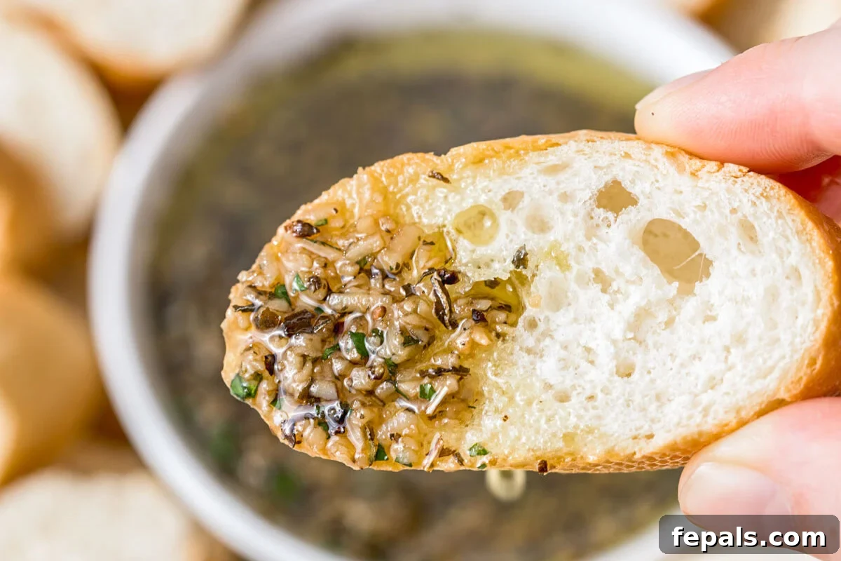 hand holding bread dipped in olive oil herb dip.