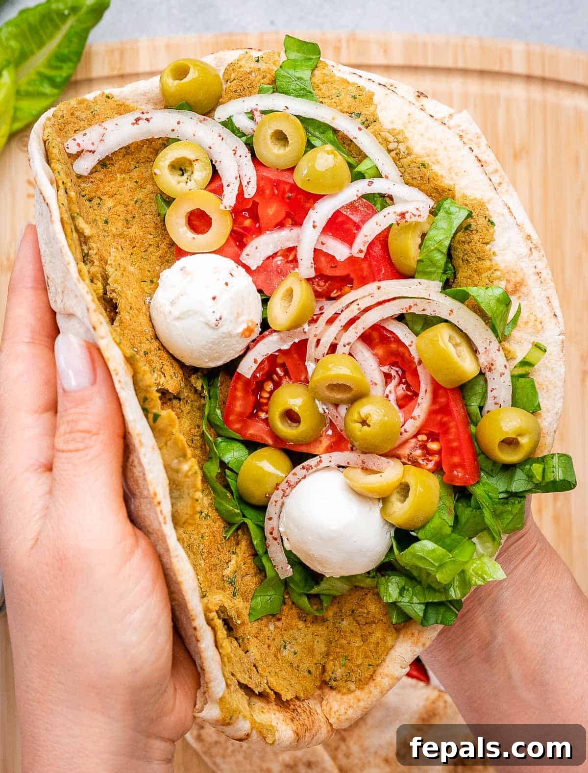 hand folding a falafel smash pita.