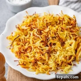 Crispy Air Fryer Frozen Hash Browns Recipe 7 crispy-looking air fryer hash browns on a white plate.