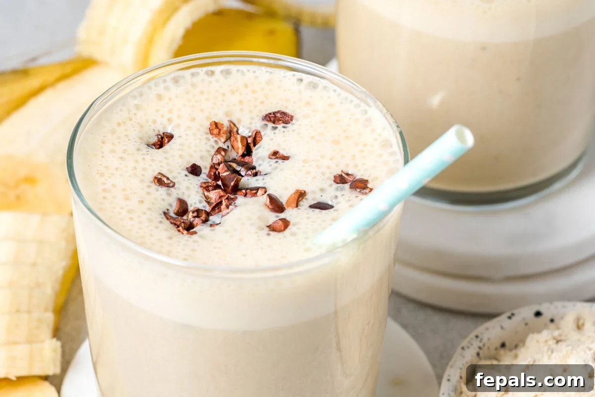 protein shake in a jar topped with cocoa nibs and has a straw in it.