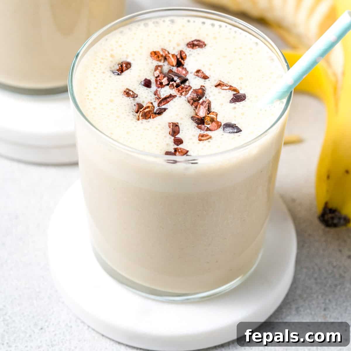 a glass with protein shake topped with cocoa nibs.