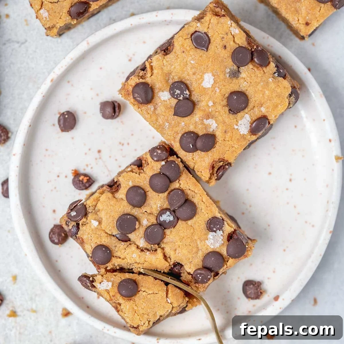 High-Protein Chocolate Chip Cookie Bars for Snackable Energy 7 2 cookie bars on a plate with a fork grabbing a bite.