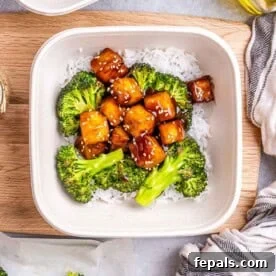 a meal prep bowl with white rice topped with teriyaki tofu bites and roasted broccoli.