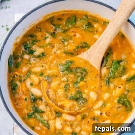 top view of white bean soup in a pot with a wooden spoonful of soup