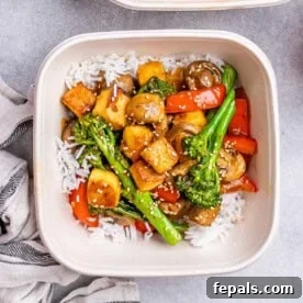 a meal prep bowl or tofu stir fry cooked with veggies served with white rice.