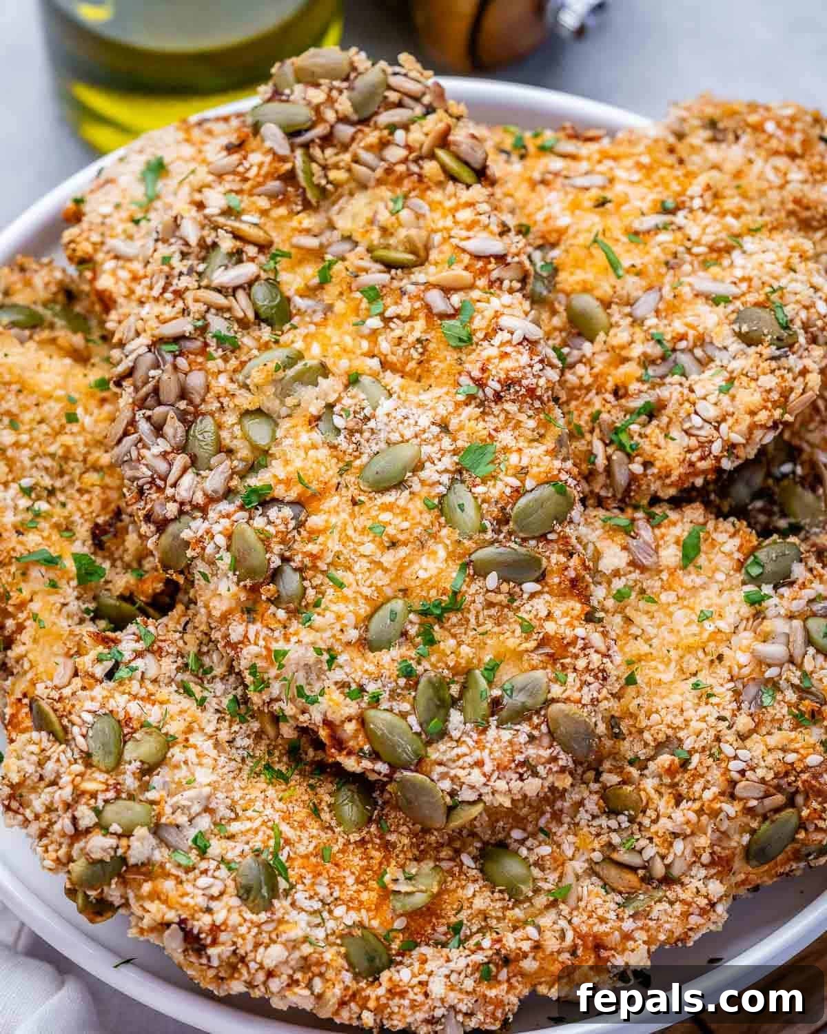 Seeded air fryer chicken cutlets on a white plate.