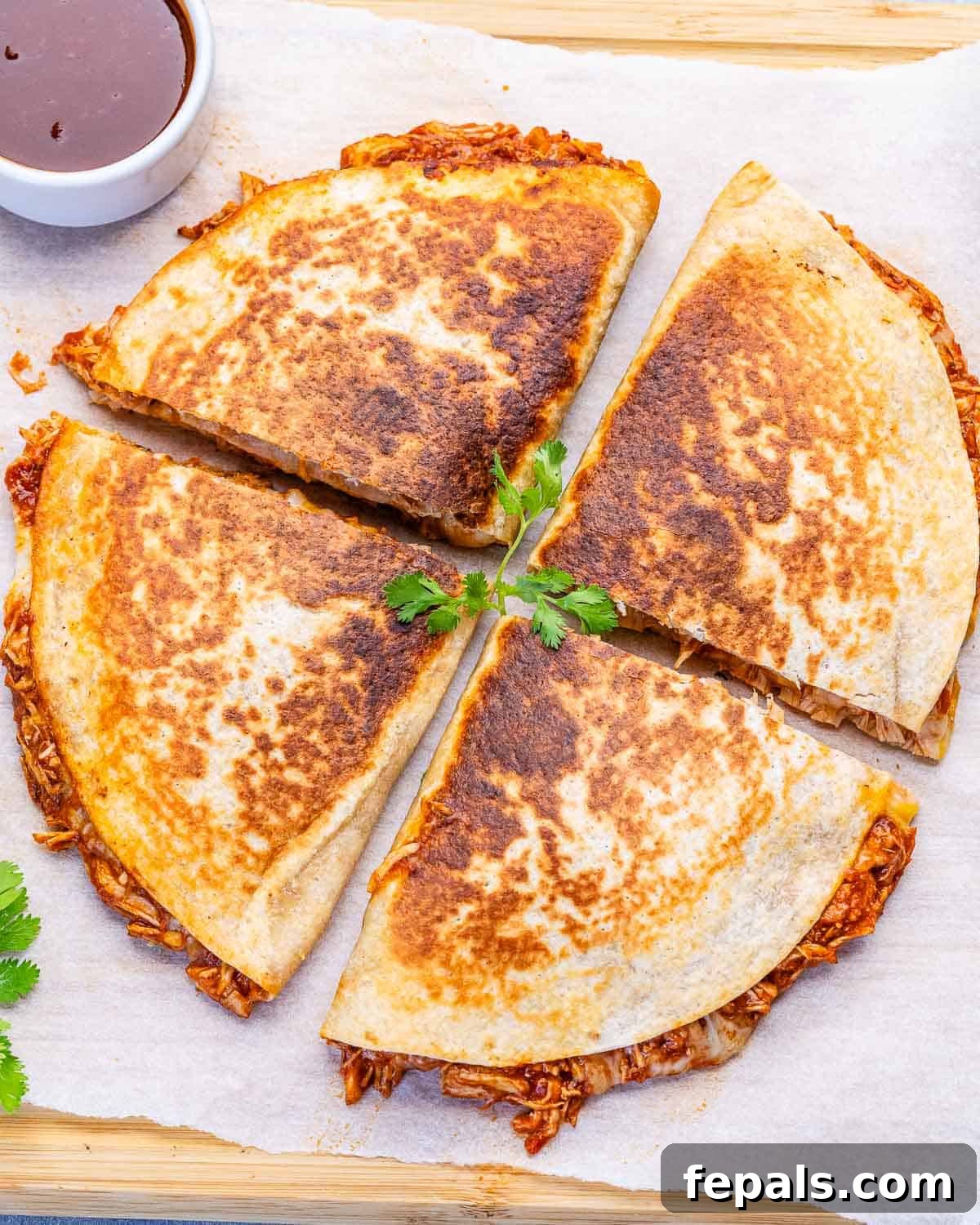 Chicken quesadilla cut into 4 parts on a cutting board.
