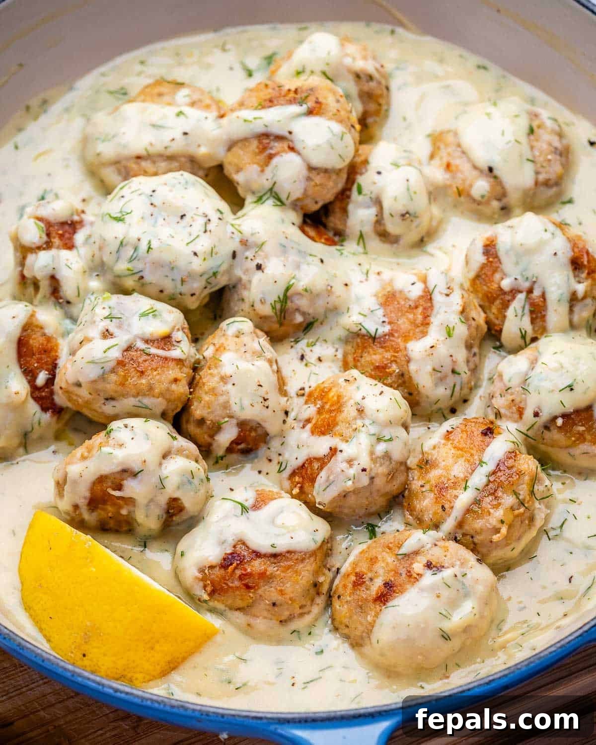 greek chicken meatballs cooked a creamy lemon sauce in a skillet.