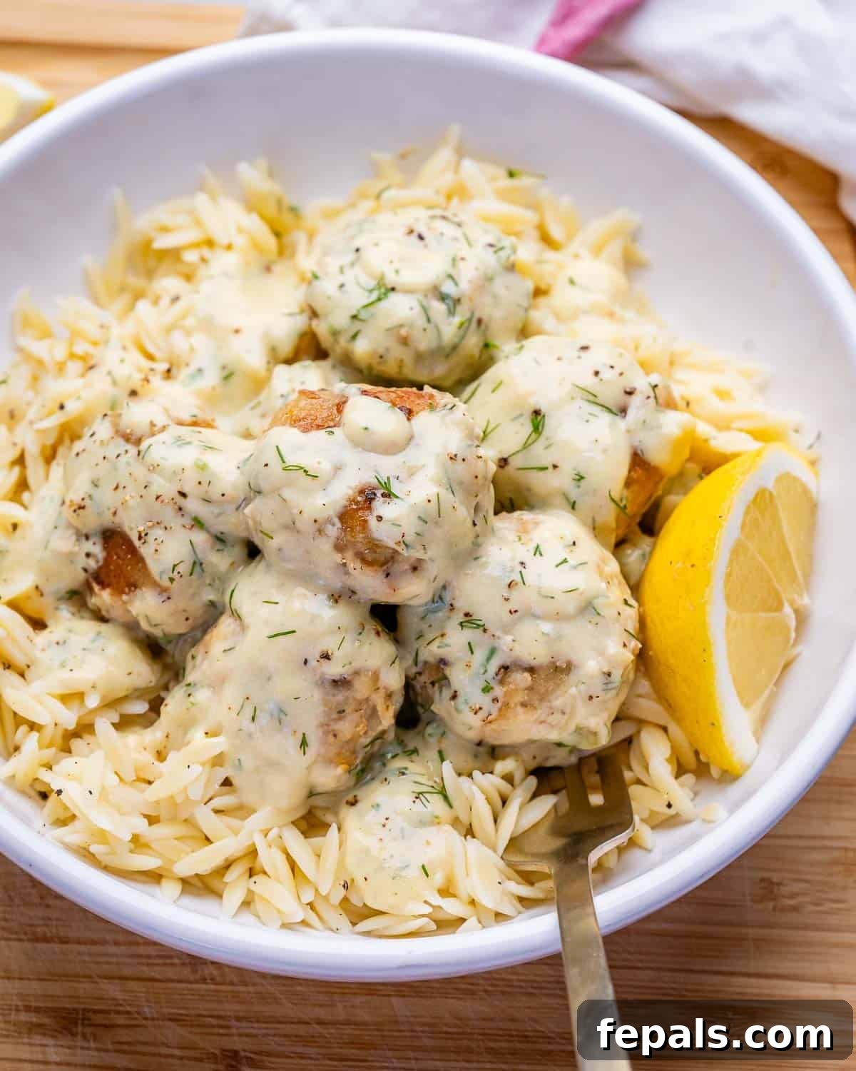 creamy chicken meatballs served over cooked orzo in a bowl.