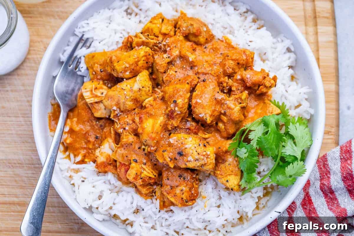 Butter chicken served over a bowl of rice.
