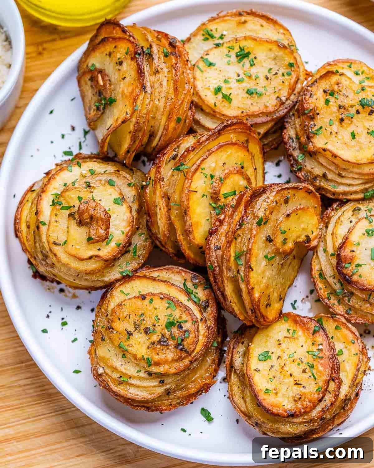 Crispy potato stacks on a white round plate garnished with parsley.