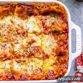 a white dish with lasagna topped with melted cheese.
