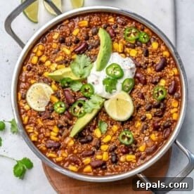 Vegetarian chili on a round skillet topped with a bit of sour cream and sliced jalapeno.