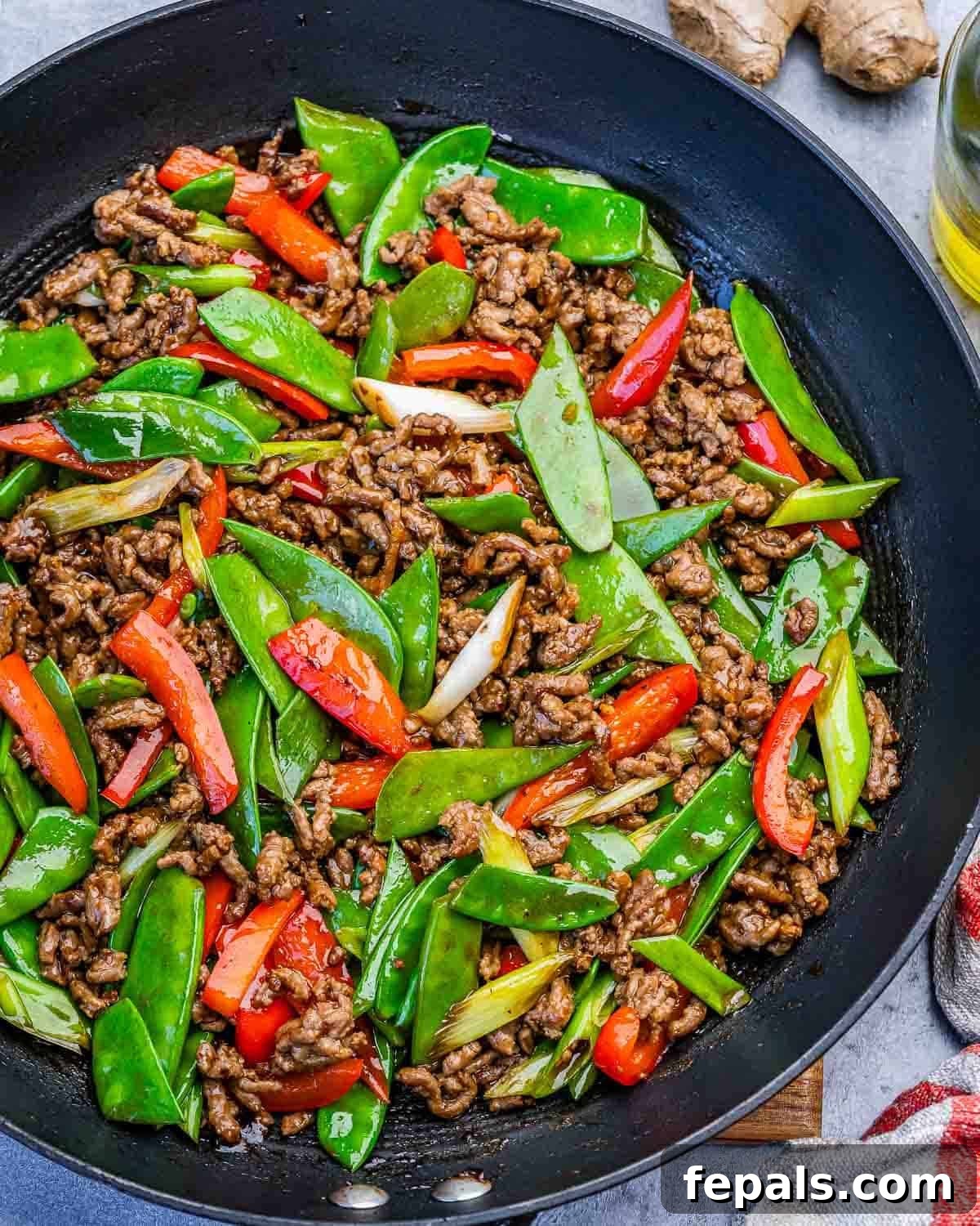 ground beef stir fry with snap peas in a skillet.