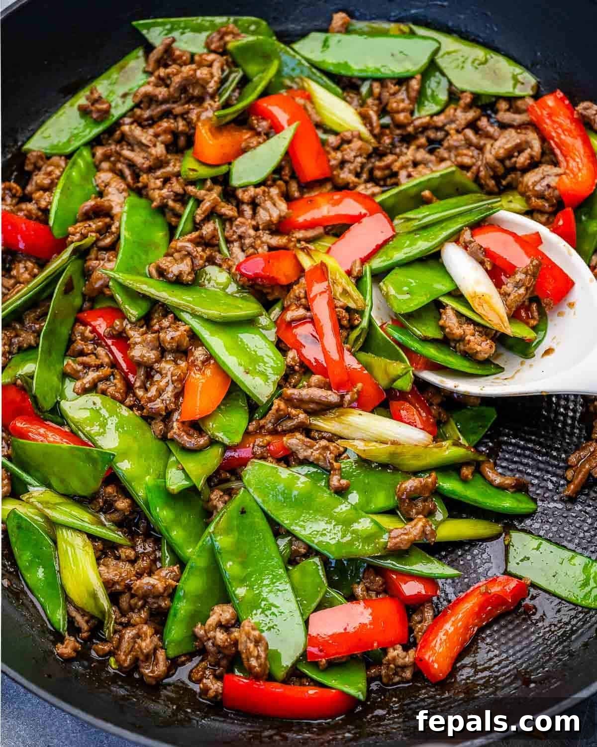 spoon in a skillet with ground beef stir fry.