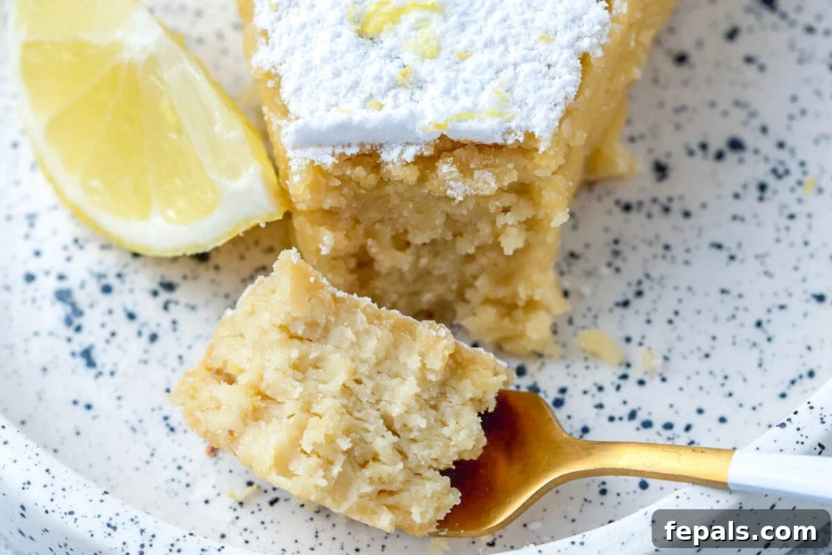 a bite taken off the lemon cake with a fork on a plate.
