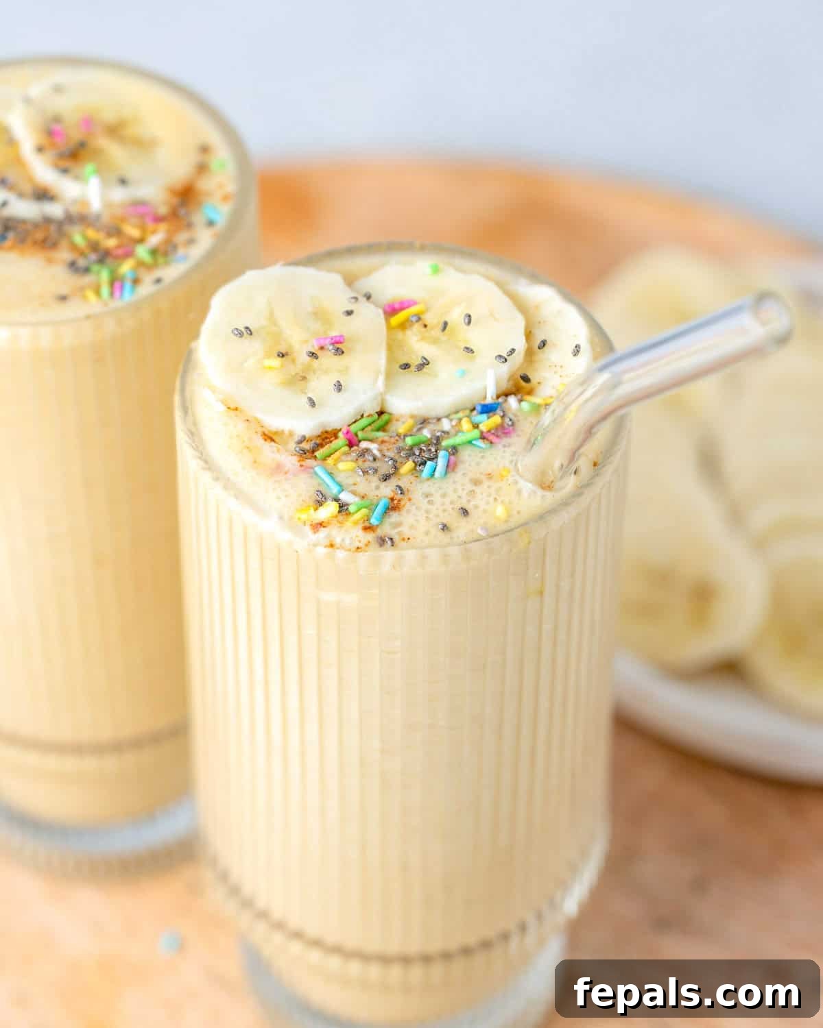 two vanilla shakes in cups on a wooden board.