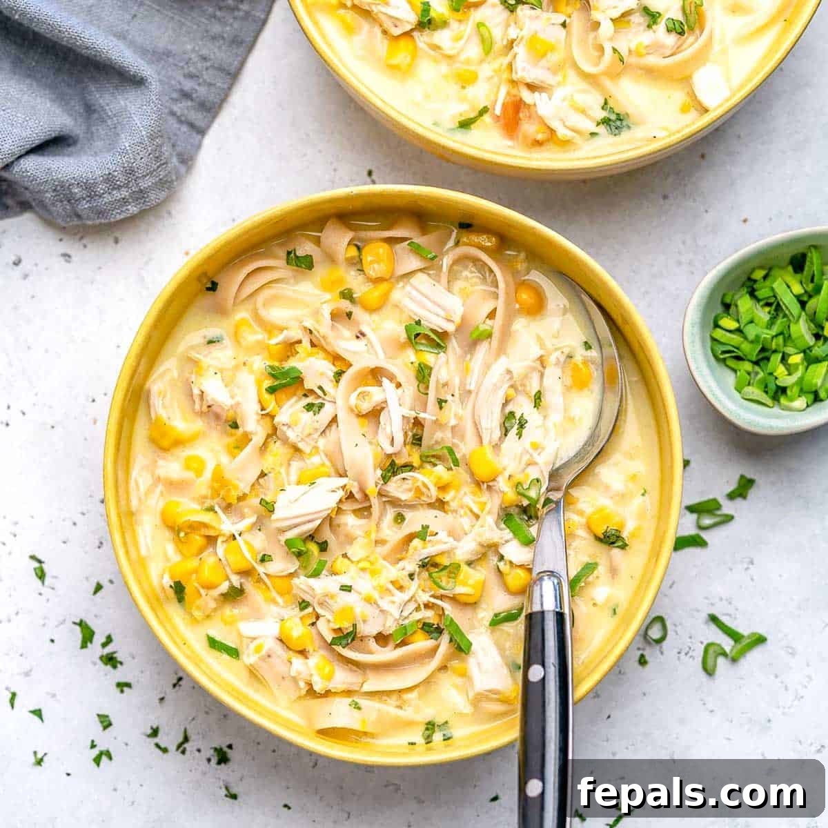 Creamy Rotisserie Chicken and Corn Soup 4 a bowl with chicken corn and noodle soup with spoon in the bowl.