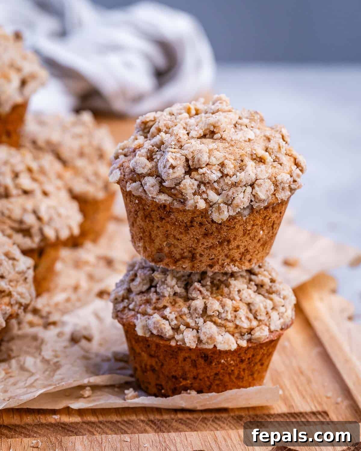 Cinnamon Streusel Muffins Recipe with Brown Sugar Crumble 2 Two cinnamon streusel muffins stacked on a wooden board.