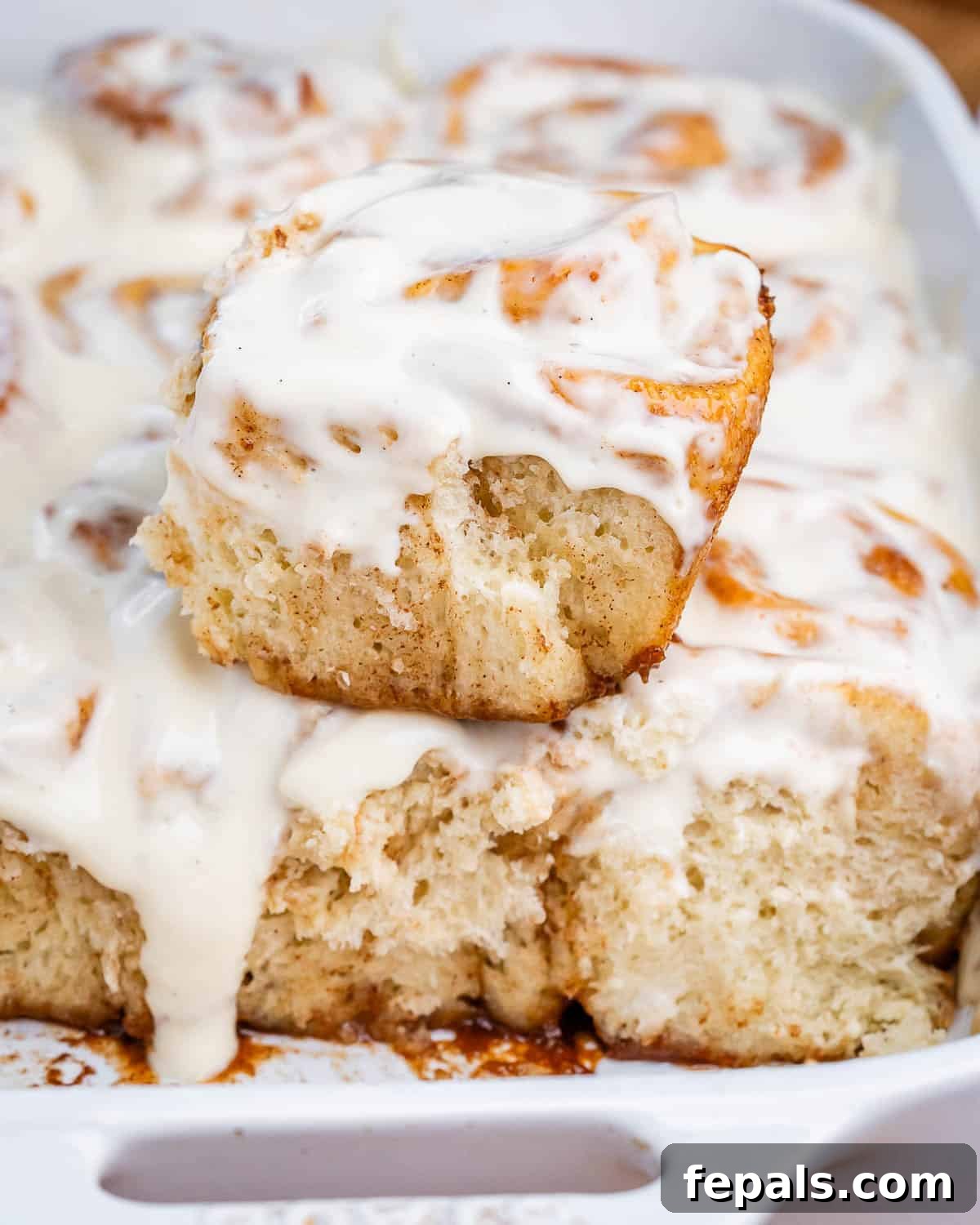 Greek Yogurt Cinnamon Rolls: Soft, Tangy, Homemade 2 A white dish with cinnamon rolls, with one roll stacked on top.
